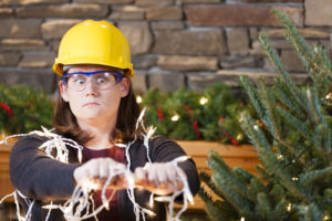 A woman in a hard hat attempting to decorate for the holidays.
