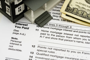 Picture of mortgage interest tax form with a toy house and money on top.