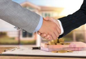 A high quality mortgage loan officer shaking hands with a new homeowner.